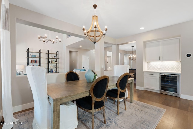 dining area featuring beverage cooler, a notable chandelier, baseboards, and wood finished floors