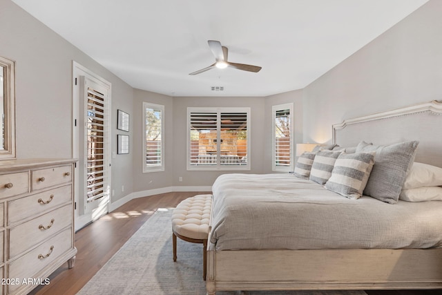 bedroom featuring visible vents, baseboards, dark wood finished floors, and a ceiling fan