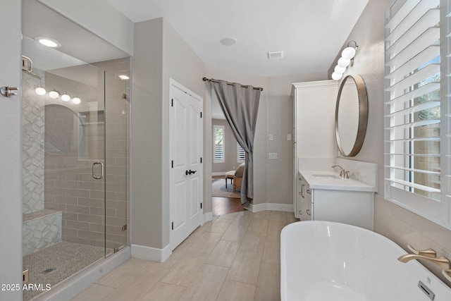 full bath with a stall shower, a freestanding bath, vanity, and baseboards