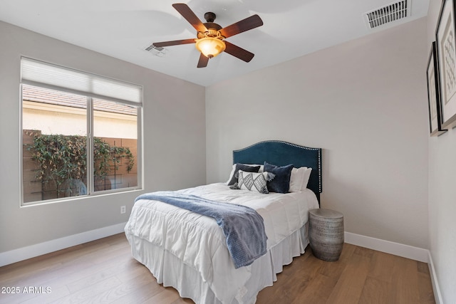 bedroom with wood finished floors, visible vents, and baseboards