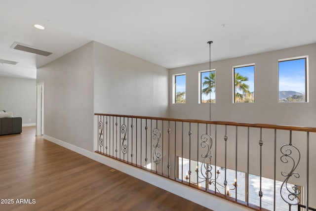 hallway with visible vents, baseboards, and wood finished floors