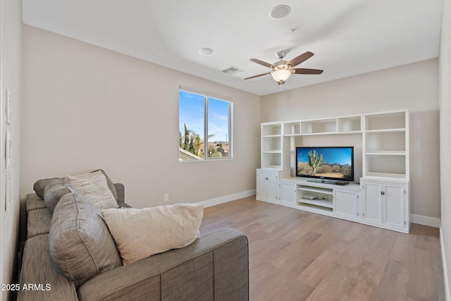 living area featuring light wood-type flooring, baseboards, visible vents, and a ceiling fan