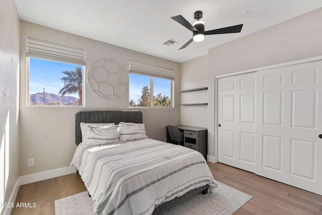 bedroom featuring ceiling fan, visible vents, baseboards, and wood finished floors