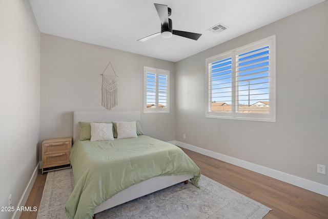 bedroom featuring visible vents, ceiling fan, baseboards, and wood finished floors