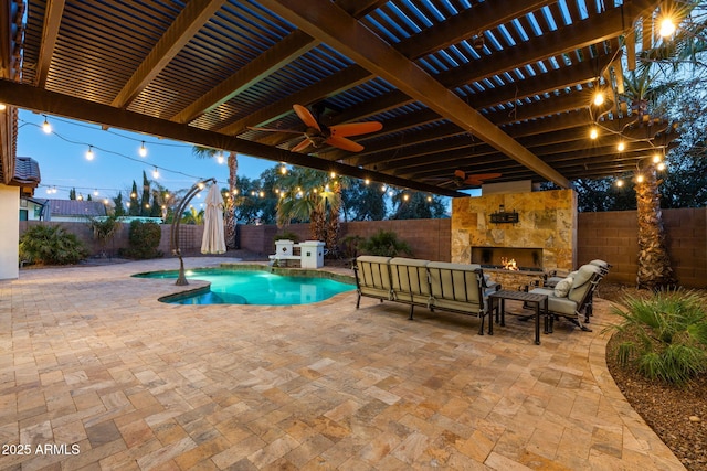 view of pool with a ceiling fan, a patio area, a fenced backyard, and an outdoor stone fireplace