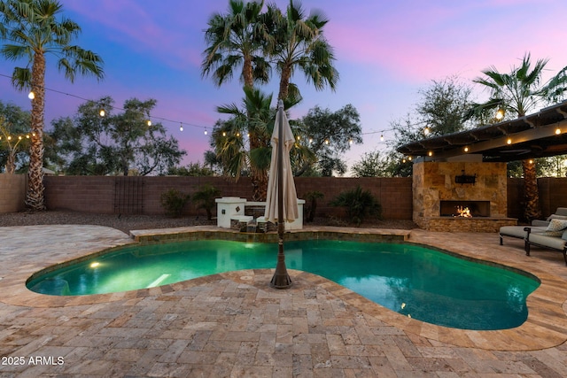 view of pool with a patio, a fenced backyard, a fenced in pool, and an outdoor stone fireplace