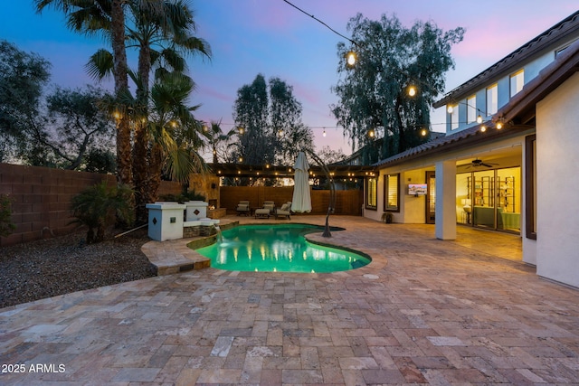 pool at dusk featuring a fenced in pool, a fenced backyard, and a patio area