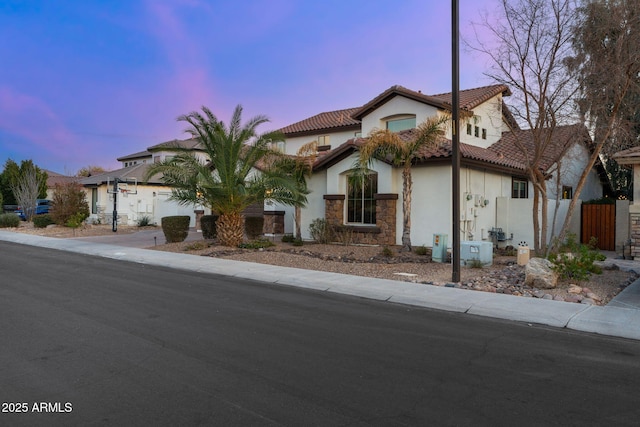 view of front of house featuring stucco siding, stone siding, concrete driveway, and a tiled roof