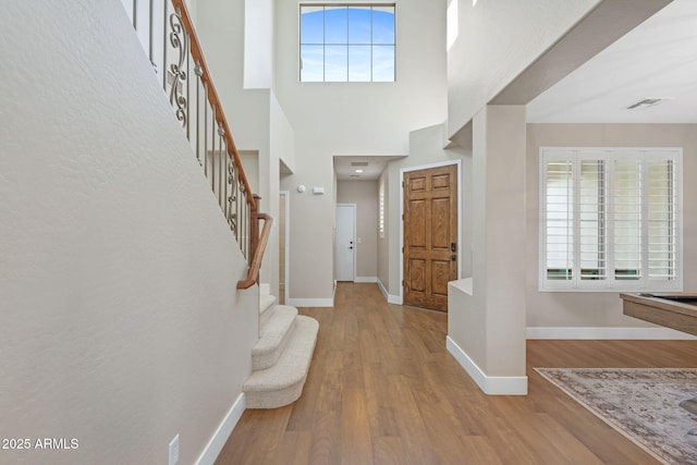 foyer entrance with visible vents, a healthy amount of sunlight, baseboards, and wood finished floors