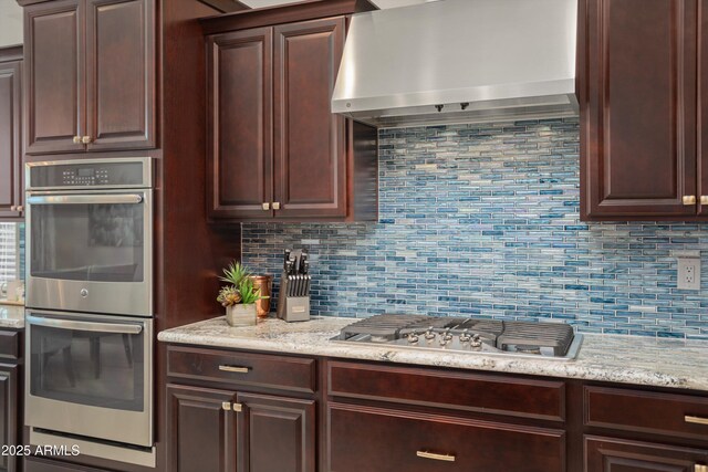 kitchen featuring dark brown cabinetry, tasteful backsplash, stainless steel appliances, and extractor fan