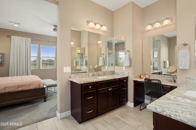 full bath with a sink, visible vents, baseboards, two vanities, and a ceiling fan