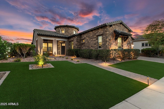 mediterranean / spanish-style house featuring a yard, stone siding, and a tiled roof