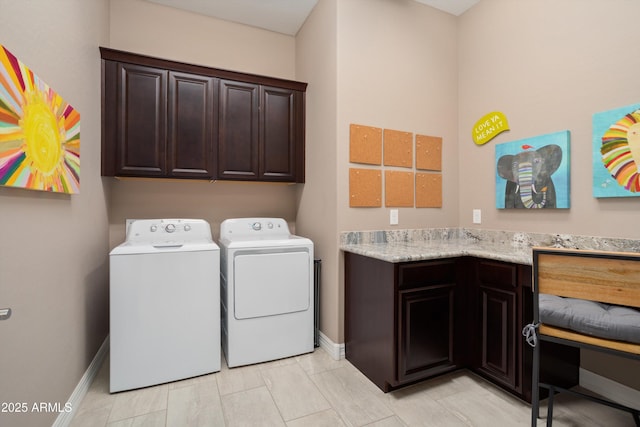 washroom with washer and dryer, cabinet space, and baseboards