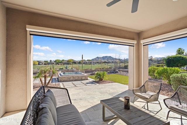 view of patio / terrace with a mountain view, ceiling fan, a fenced backyard, and an in ground hot tub