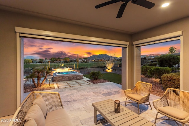 view of patio / terrace with ceiling fan, an in ground hot tub, and a fenced backyard