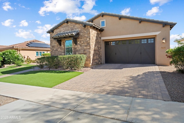 view of front of home with stucco siding, a garage, a tile roof, driveway, and stone siding
