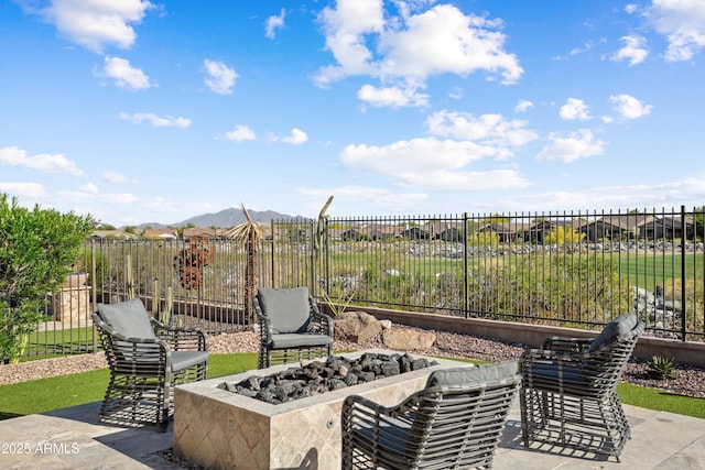 view of patio with fence, an outdoor fire pit, and a mountain view