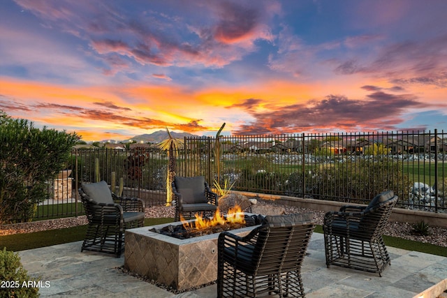 patio terrace at dusk with a mountain view, fence, and an outdoor fire pit