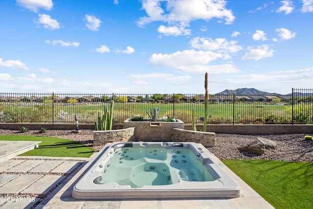 view of pool featuring fence, a lawn, a mountain view, and an outdoor hot tub