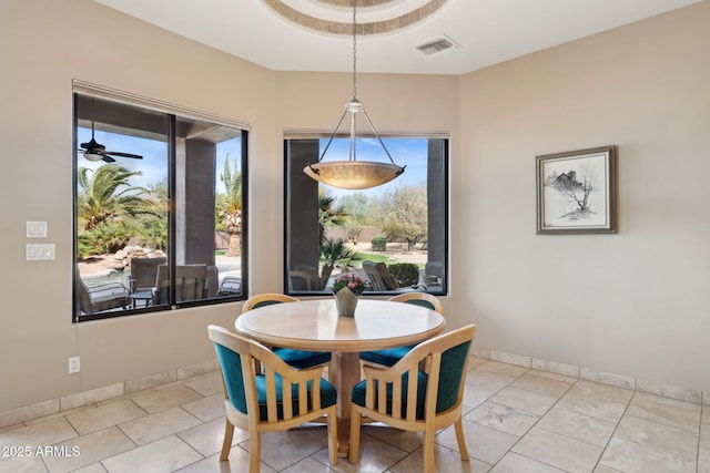 dining space with ceiling fan, a raised ceiling, visible vents, and baseboards