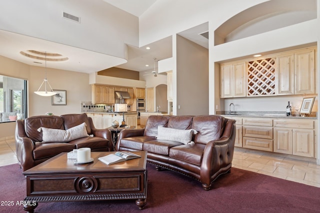 living room with visible vents, arched walkways, a towering ceiling, wet bar, and recessed lighting