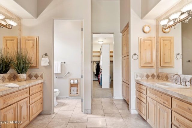 bathroom featuring two vanities, a sink, a notable chandelier, and toilet