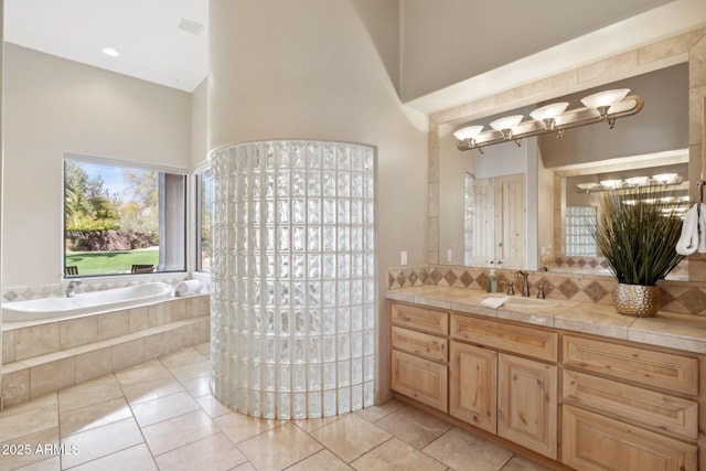 full bathroom featuring a garden tub, a towering ceiling, decorative backsplash, vanity, and tile patterned flooring