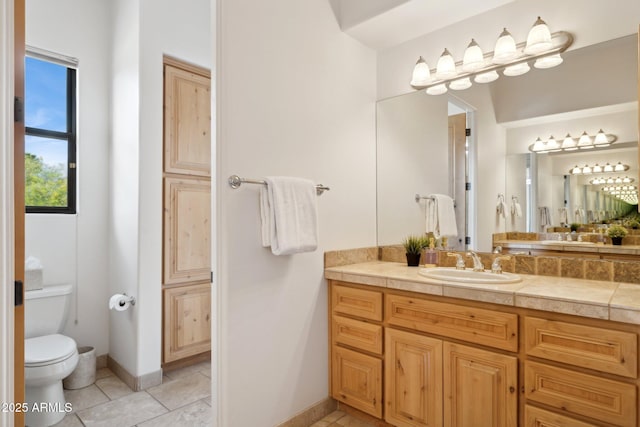 bathroom featuring baseboards, vanity, toilet, and tile patterned floors