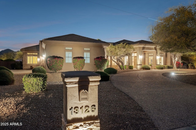 view of front facade featuring curved driveway and stucco siding