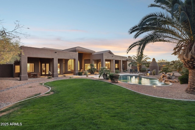 back of property with an outdoor pool, a yard, a patio area, and stucco siding