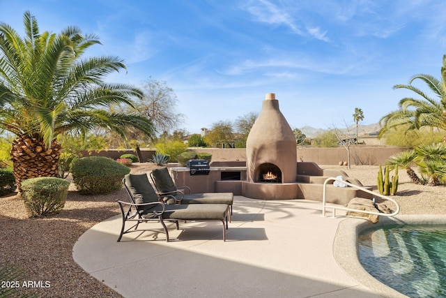 view of patio / terrace with a warm lit fireplace and fence