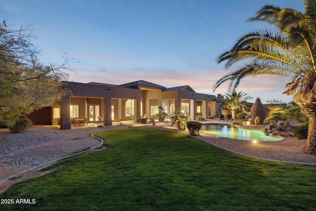 rear view of property with an outdoor pool, a yard, a patio area, and stucco siding