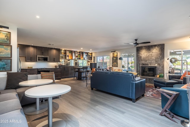 living area featuring recessed lighting, a fireplace, light wood finished floors, and ceiling fan