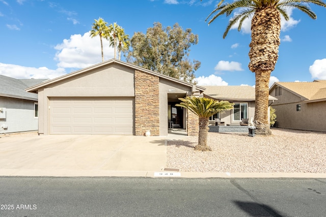 view of front of house featuring an attached garage, stone siding, driveway, and stucco siding