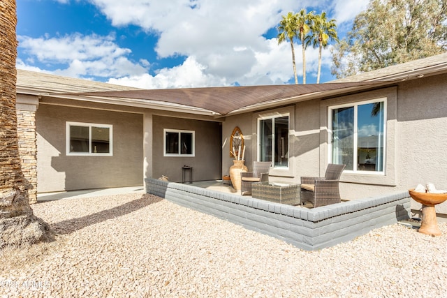 rear view of property with stucco siding and a patio