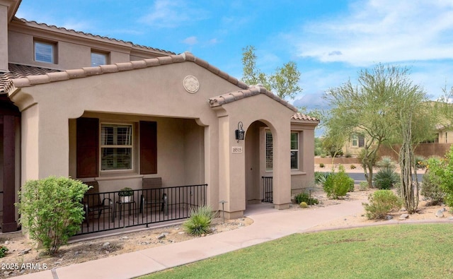 view of exterior entry with a tile roof and stucco siding