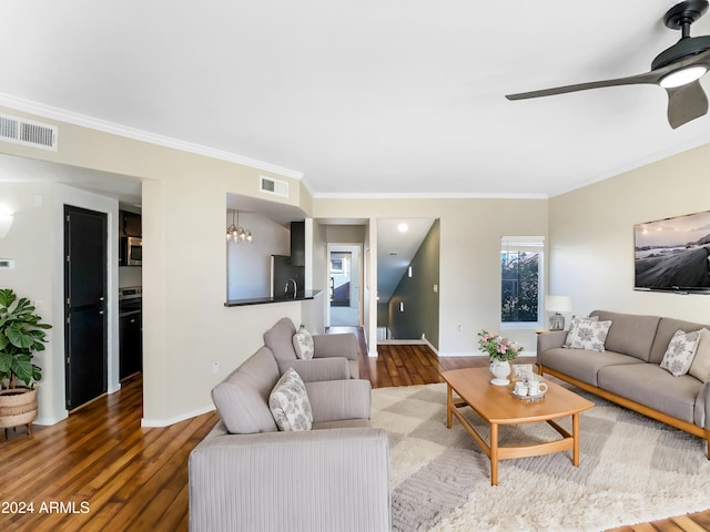 living room with hardwood / wood-style flooring, ceiling fan with notable chandelier, and crown molding