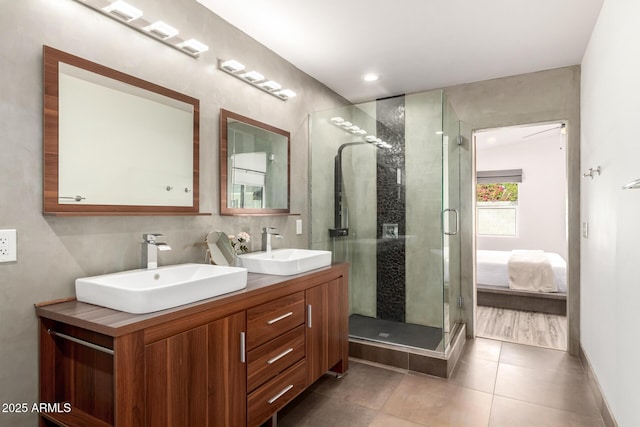 ensuite bathroom with a sink, tile patterned floors, a stall shower, and double vanity