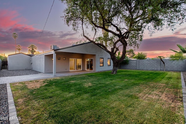 back of property with stucco siding, a patio area, fence, and a yard