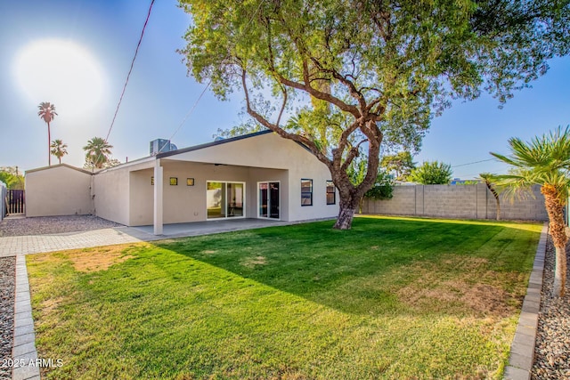 rear view of property with central AC, a patio, a fenced backyard, stucco siding, and a yard