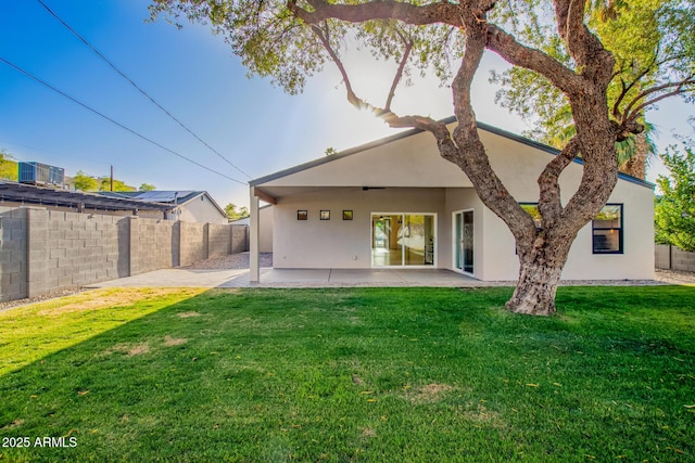 rear view of house featuring a lawn, a patio, fence, and stucco siding