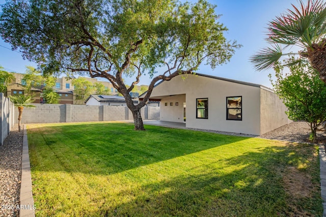 rear view of house with a fenced backyard, a patio, stucco siding, and a lawn