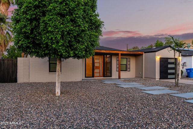 view of front of house featuring stucco siding, fence, and a garage