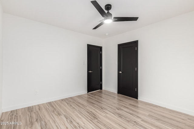 spare room with baseboards, ceiling fan, and light wood-type flooring