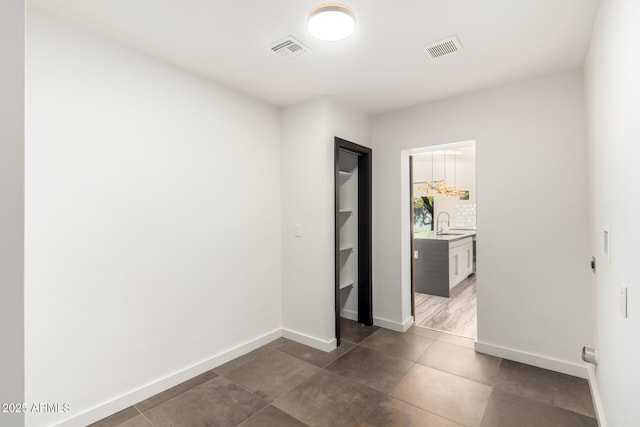 unfurnished bedroom with dark tile patterned floors, baseboards, visible vents, and a sink