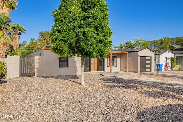view of front facade with an attached garage, stucco siding, and fence