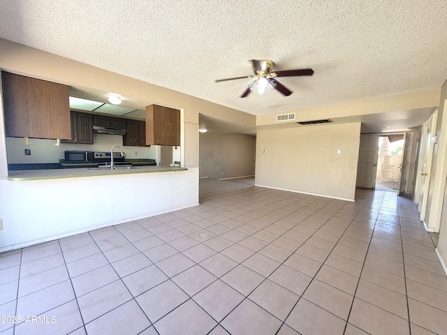 15602 N 55th Ave, Glendale, AZ 85306 - kitchen with black microwave, under cabinet range hood, a textured ceiling, a ceiling fan, and light tile patterned floors