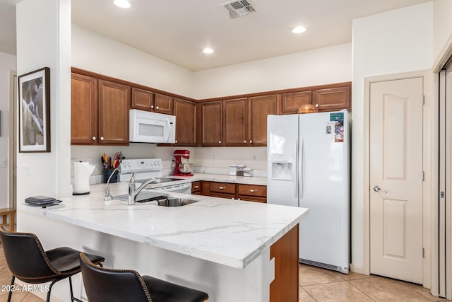 kitchen featuring a kitchen breakfast bar, white appliances, light stone countertops, light tile patterned floors, and kitchen peninsula