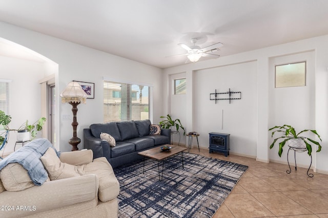 tiled living room with ceiling fan and a wood stove