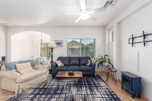 living room with a wood stove, ceiling fan, and tile patterned flooring